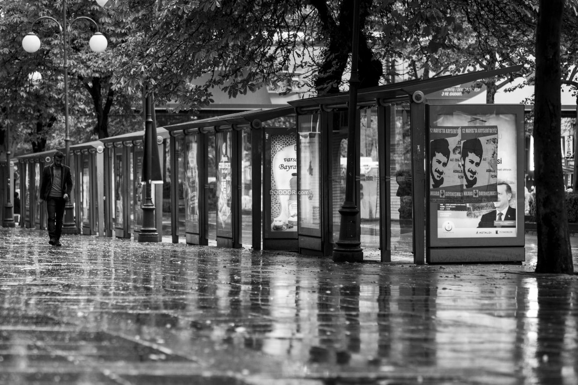 00724_黑白色照片记录下雨天城市湿滑的路面和一个孤独的行人.jpg