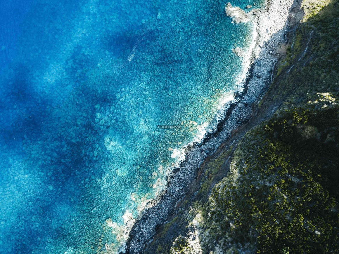 01166_清澈蔚蓝的海水冲击着山底的礁石溅起洁白的浪花.jpg