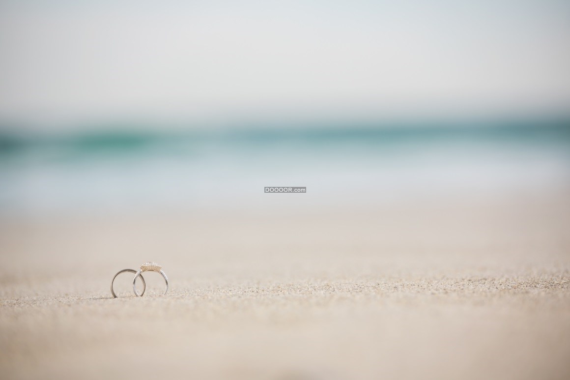 10155_一对结婚戒指在沙滩上象征爱情的钻戒.jpg