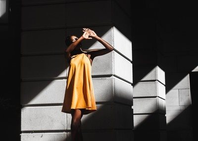 女士平面模特灰色的建筑阳光投射黄色的T恤姿势优雅
